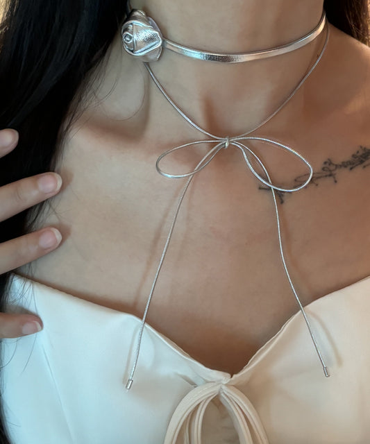 Elegante collar con lazo de dos capas de rosas y cuerda de cuero y seda