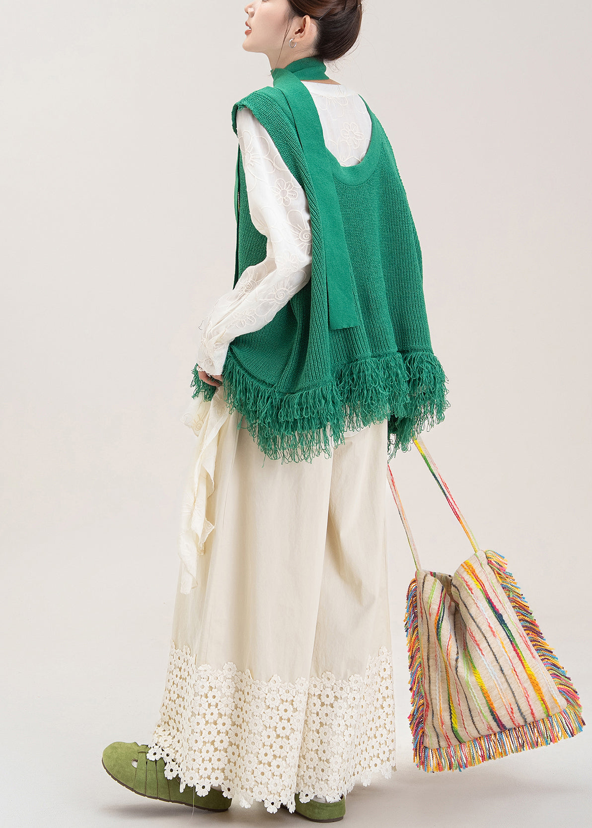Conjunto de tres piezas: chaleco de punto con borlas verdes y pantalones anchos color albaricoque.