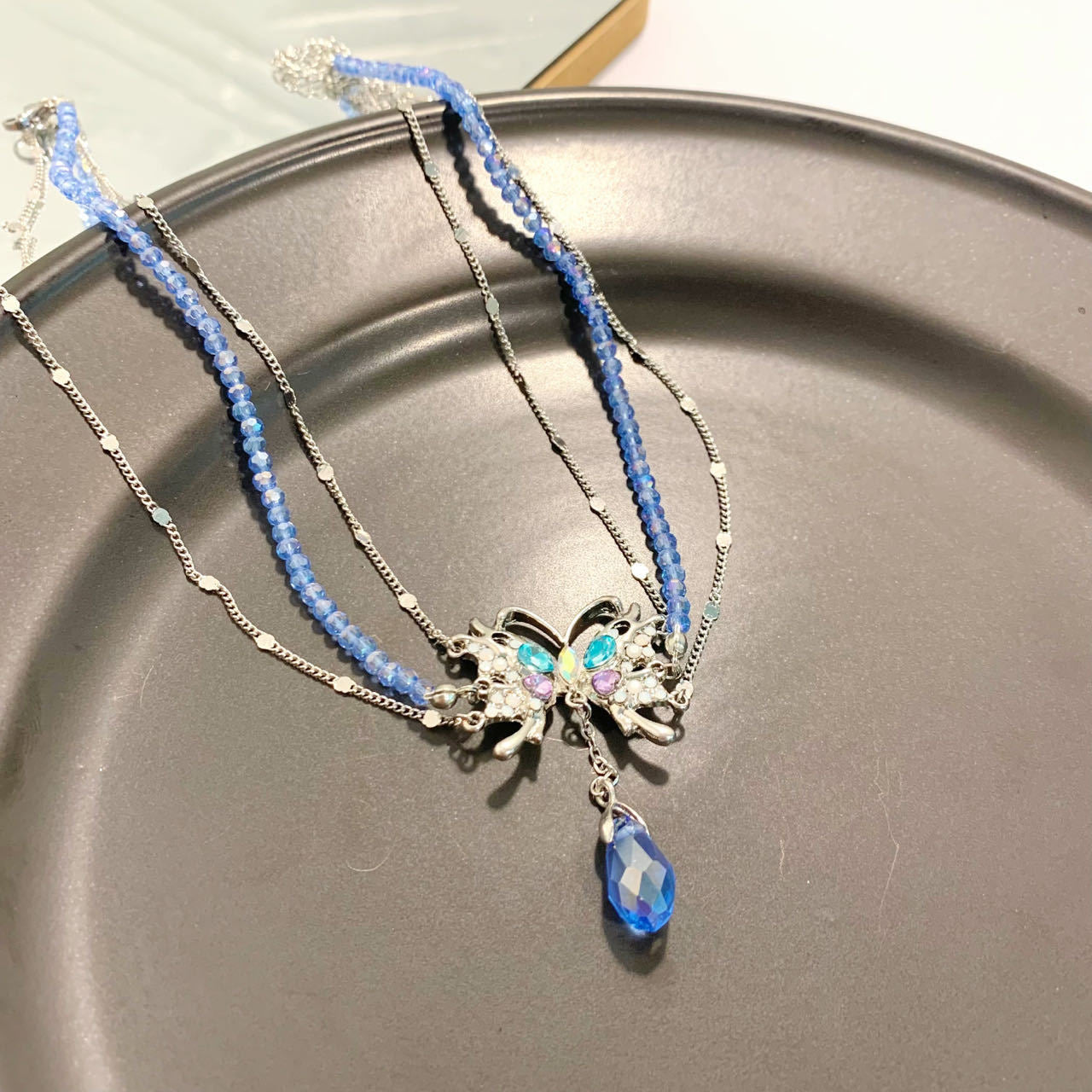 Wunderschöne Halskette mit Anhänger aus Kupfer mit Zirkonia-Kristallen in Babyblau mit Schmetterlings- und Wassertropfen-Quaste