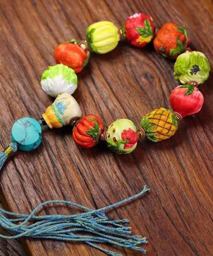 Hermosa pulsera con borlas de frutas y verduras tejida a mano con bloques de color