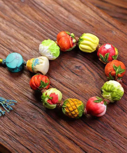 Hermosa pulsera con borlas de frutas y verduras tejida a mano con bloques de color
