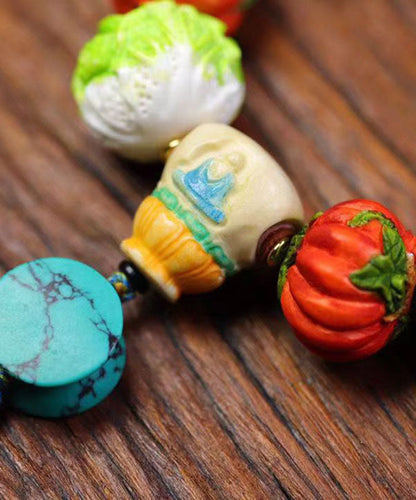 Hermosa pulsera con borlas de frutas y verduras tejida a mano con bloques de color