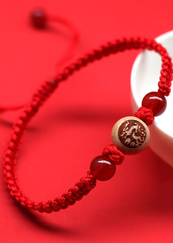 Elegante pulsera roja tejida a mano con dijes de madera de melocotón