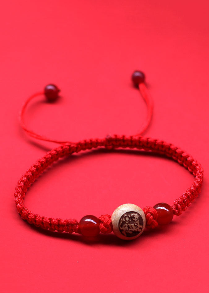 Elegante pulsera roja tejida a mano con dijes de madera de melocotón