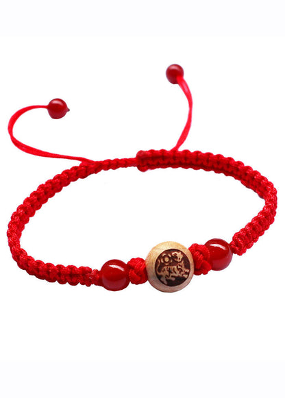 Elegante pulsera roja tejida a mano con dijes de madera de melocotón