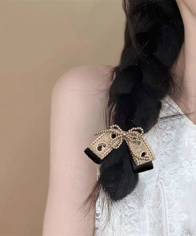 Niedliche Haarnadel mit Perlenschleife aus Textilhandwerk in Kaffeefarben.