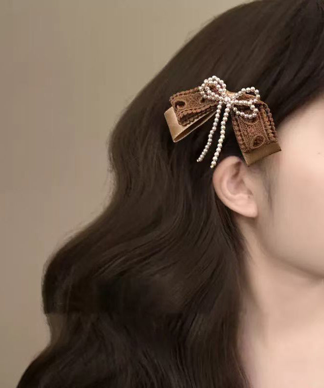 Niedliche Haarnadel mit Perlenschleife aus Textilhandwerk in Kaffeefarben.