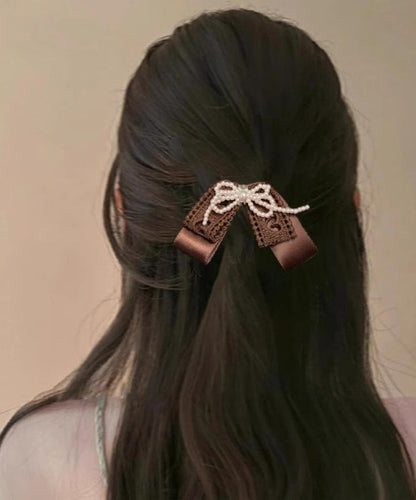 Niedliche Haarnadel mit Perlenschleife aus Textilhandwerk in Kaffeefarben.