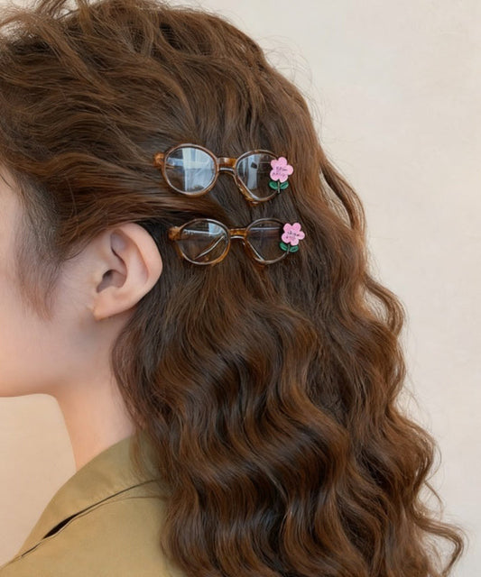 Bonitas gafas de acrílico rosa con diseño floral y horquilla para el pelo.