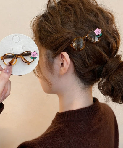 Bonitas gafas de acrílico rosa con diseño floral y horquilla para el pelo.
