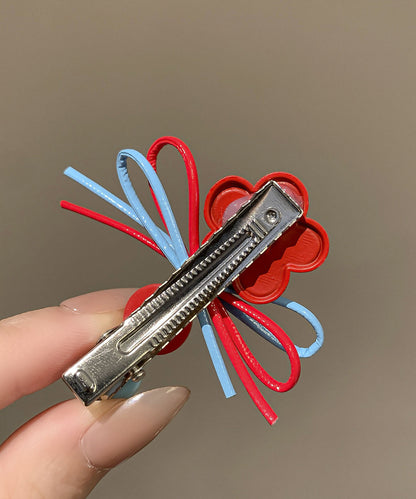 Un par de horquillas para el pelo con diseño de mariposas y flores de acrílico arcoíris