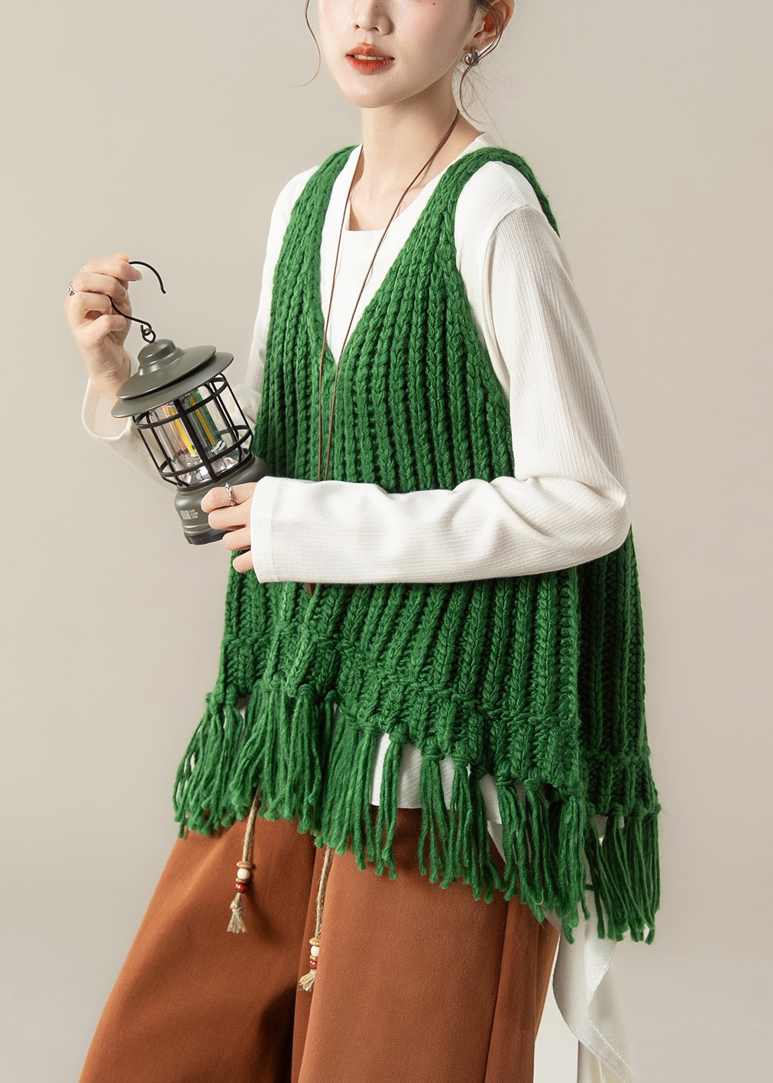 Elegante conjunto de dos piezas de chaleco de punto verde con cuello en V y borlas y camiseta de algodón blanca para primavera.