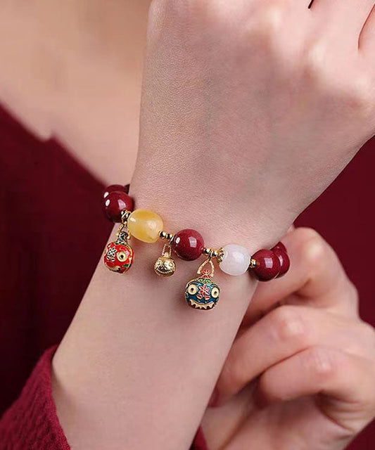 Elegante pulsera con dije de bestia dorada que traga arena morada y dorada