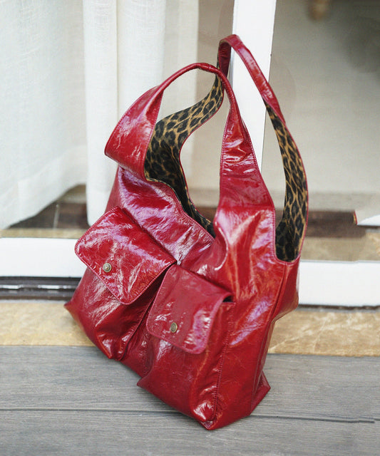 Elegante bolso de hombro de piel sintética con forro de leopardo en color rojo y bolsillos.