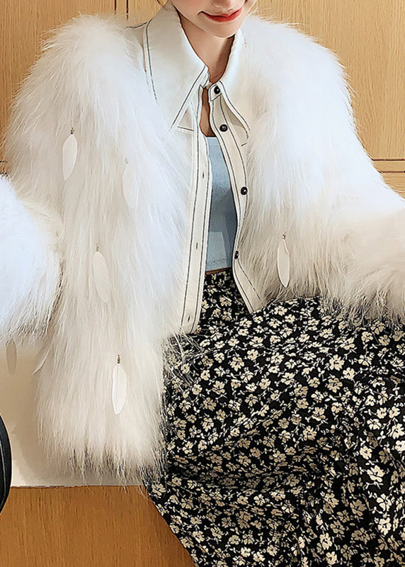 Elegante abrigo de piel y cuero con borlas de plumas y cuello de mapache blanco para invierno.