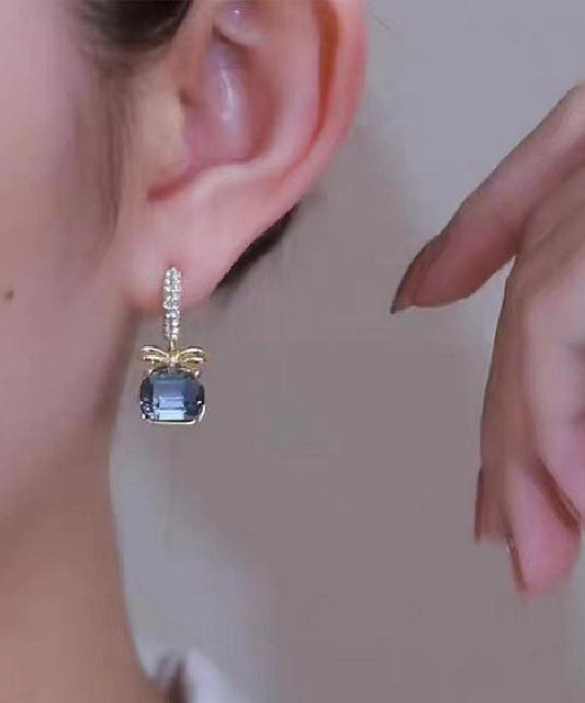 Pendientes colgantes con lazo de cristal y circonita dorada de color morado oscuro.