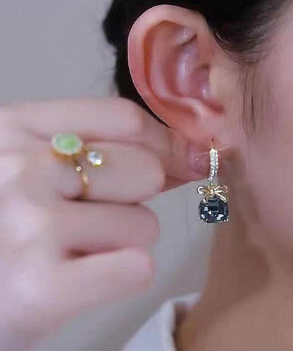 Pendientes colgantes con lazo de cristal y circonita dorada de color morado oscuro.