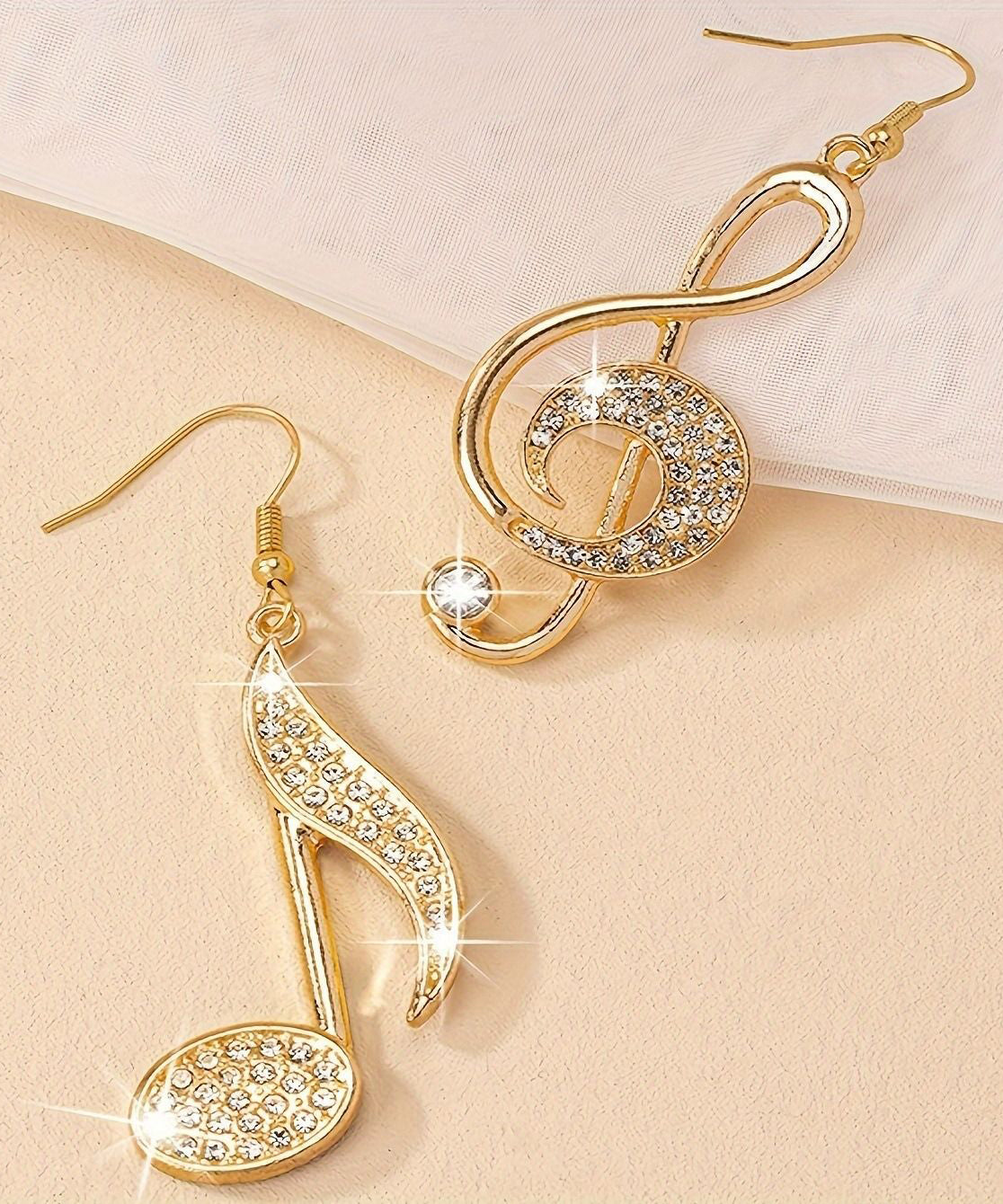 Modische Ohrringe mit asymmetrischem Anhänger in Musiknotenform, vergoldet mit Zirkonia und Kupferüberzug.