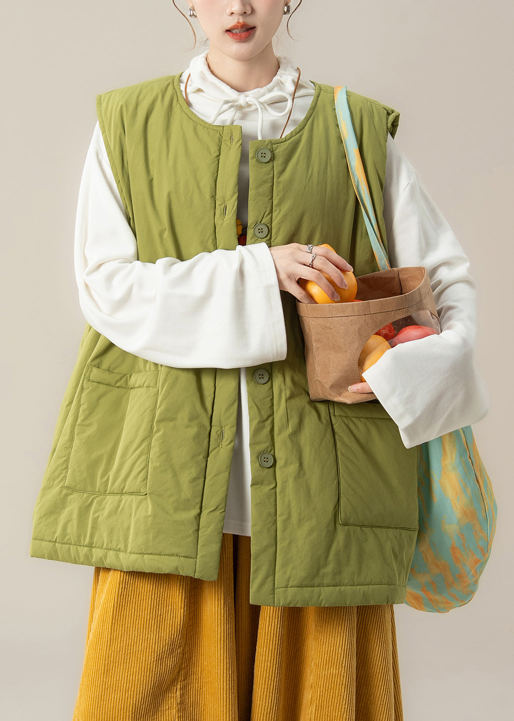 Conjunto de dos piezas sin mangas con chaleco verde de algodón fino relleno y top blanco.