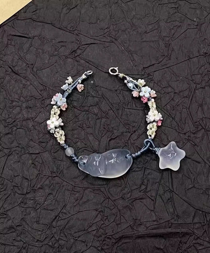 Pulsera con dijes de estrellas y gatos de Osmanthus azul tejida a mano