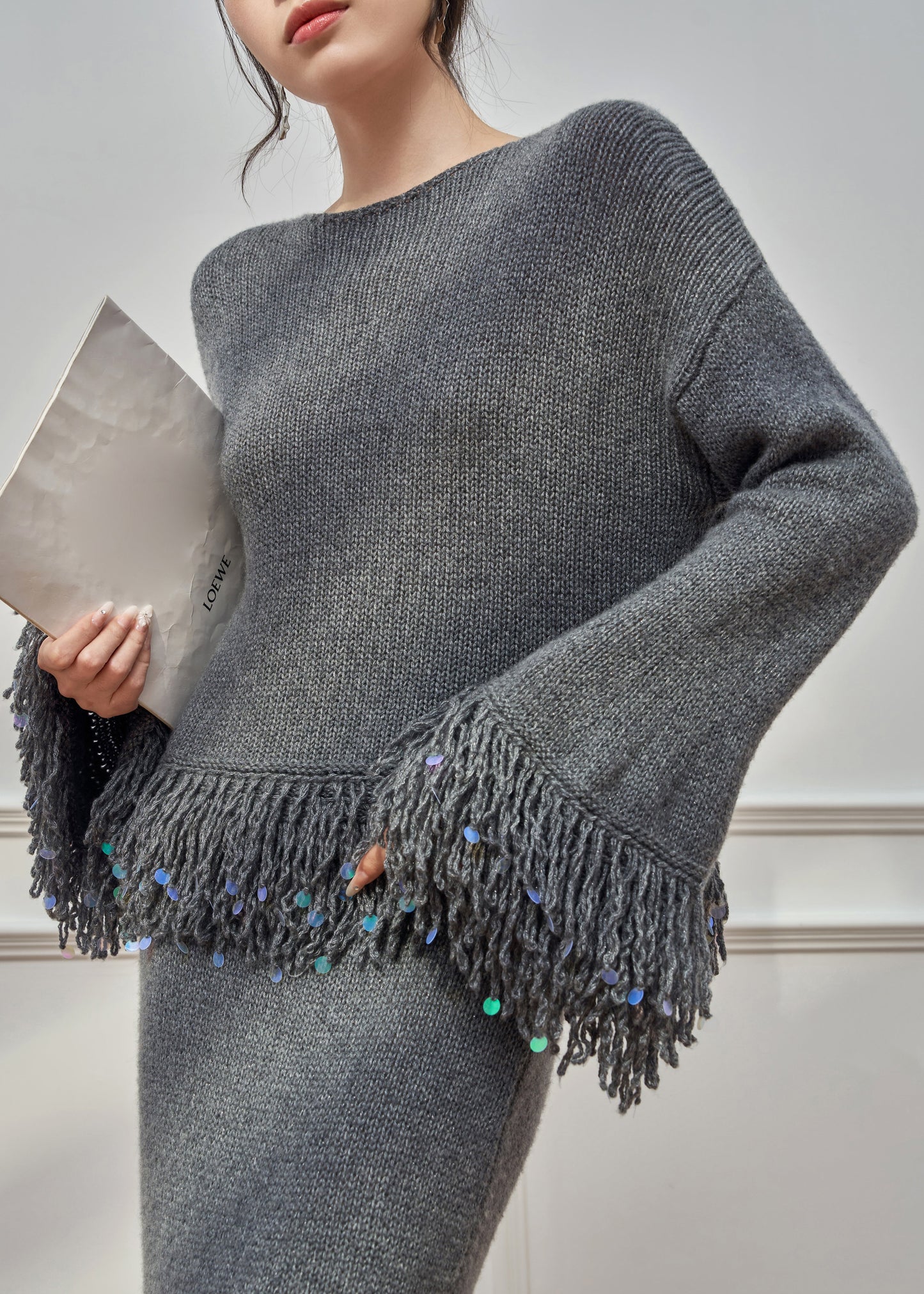 Locker sitzender, grauer Strickpullover und Rock mit Rundhalsausschnitt und Quasten, zweiteilig, mit ausgestellten Ärmeln