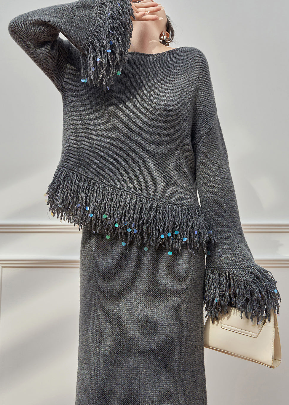 Locker sitzender, grauer Strickpullover und Rock mit Rundhalsausschnitt und Quasten, zweiteilig, mit ausgestellten Ärmeln