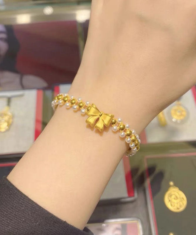 Elegante pulsera con dije de lazo de perlas tejidas a mano en amarillo y blanco
