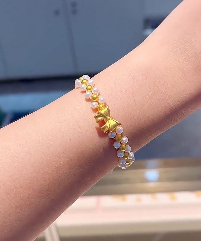 Elegante pulsera con dije de lazo de perlas tejidas a mano en amarillo y blanco