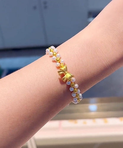 Elegante pulsera con dije de lazo de perlas tejidas a mano en amarillo y blanco